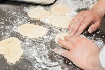 Hands kneading dough on floured surface.