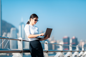Business woman working on notebook outdoor in Hong Kong City
