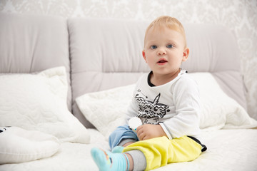 Naklejka premium Playful little boy wearing blue pyjamas in bed