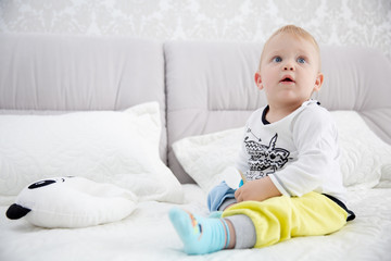 Naklejka premium Playful little boy wearing blue pyjamas in bed