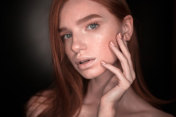Redhead girl woman with healthy glow wet skin posing isolated over black wall background looking camera touching face take care.