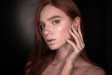 Redhead girl woman with healthy glow wet skin posing isolated over black wall background looking camera touching face take care.