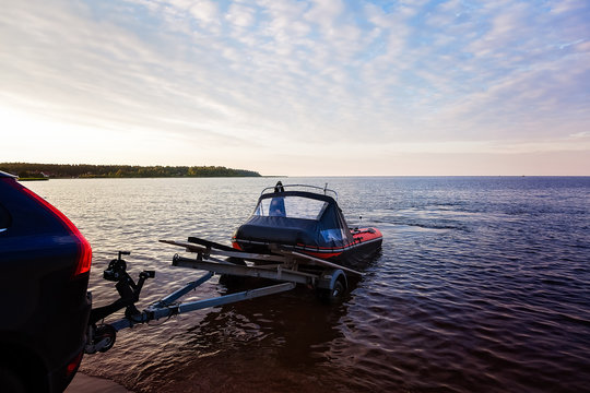 Loading a rubber boat on a trailer on the lake at sunset
