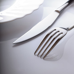 Empty plate with knife and fork on a white background