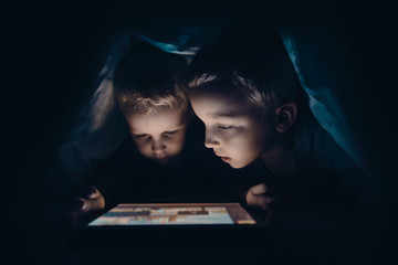 Two kids with tablet computer in a dark room