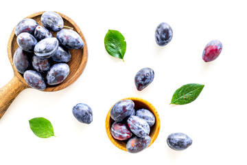 Blue plum for dessert. Purple plum and leaves pattern on white background top view