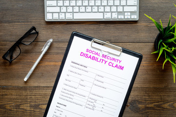 Social security. Disability claim form near glasses on dark wooden background top view space for text
