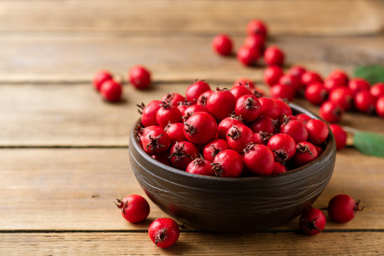 Crataegus or hawthorn berries in ceramic bowl on rustic wooden background. Selective focus.