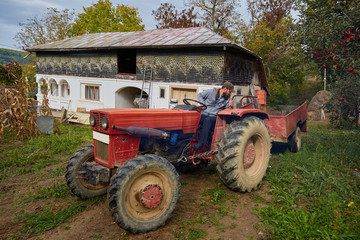 Obraz premium Farmer driving tractor through backyard orchard