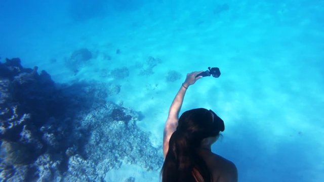 Female scuba diver swims through reef in Tahiti, POV