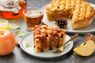 Slice of apple pie with caramel sauce on a  plate. Grey background. Close up.