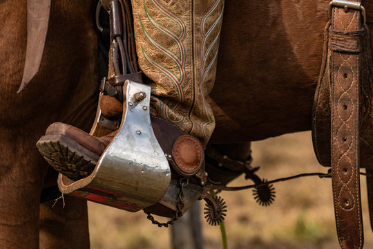Lovely crafted stirrups and saddle, american cowboy warming up before rodeo performance on new ranch
