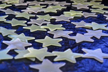 white and yellow plastic stars randomly scattered on a black and blue shiny background