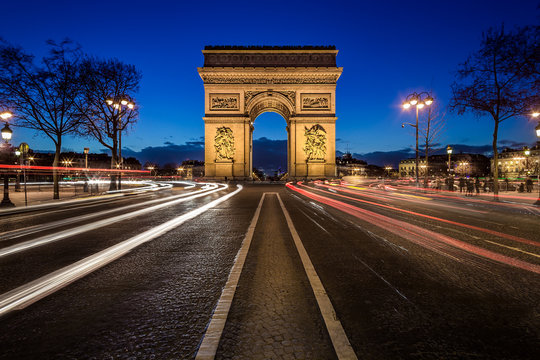 Arc de triomphe de nuit vu depuis les Champs-Elys&eacute;es avec des fil&eacute;s de lumi&egrave;re de voitures
