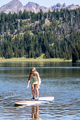 Active fit woman on a Stand up paddleboard boating on Todd Lake in the Cascade Lakes area in Bend Oregon on a sunny day
