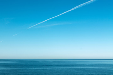 Trail from the inversion of the aircraft in the sky over the transparent open sea