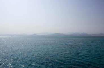 Fototapeta premium Blue sea and blue sky with sun. Mountains view on the horizont