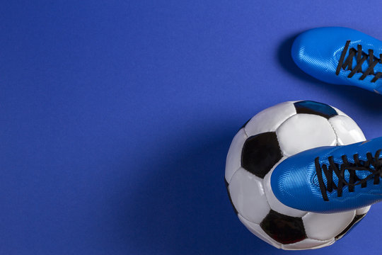 Soccer ball under soccer players feet on blue background