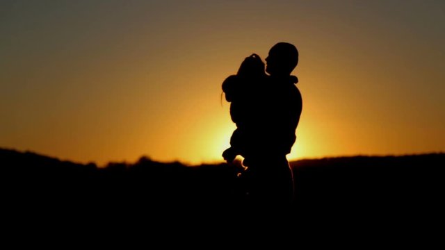 Father and daughter play at sunset.  Dad hugs and throws up his daughter at sunset.
