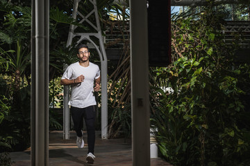 young man running through nature with white shirt and black pants