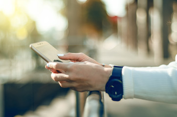 Young woman sweater in hand smartphone mobile phone in the street