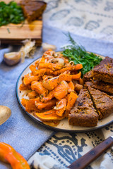 Traditional autumn baked pumpkin squash fried sticks with onion, olive oil, herbs, paprika.  Vegan lunch with homemade rye bread and fresh parsley, vegetarian dinner, healthy food.