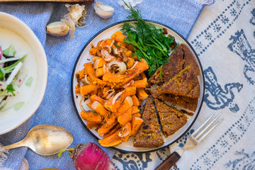 Traditional autumn baked pumpkin squash fried sticks with onion, olive oil, herbs, paprika.  Vegan lunch with homemade rye bread and fresh parsley, vegetarian dinner, healthy food.