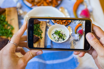 Smartphone photography of food. Woman hands holds mobile phone and take or make beautiful trendy...