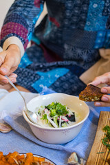 Woman hands holds okroshka - a cold soup made from cucumber, kvass, radish, dill, parsley. Vegan raw okroshka with coconut milk yoghurt, lemon, garlic. Vegetarian lunch or dinner. Healthy food.