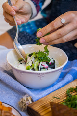 Woman hands holds okroshka - a cold soup made from cucumber, kvass, radish, dill, parsley. Vegan raw okroshka with coconut milk yoghurt, lemon, garlic. Vegetarian lunch or dinner. Healthy food.