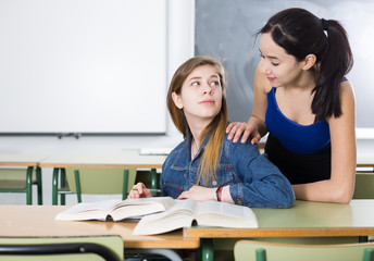 Girl is helping girlfriend with homework at the desk