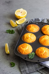 Homemade lemon muffins in black teflon baking dish over grey concrete background. Copy space.