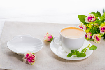 white cup of coffee on a background of scattered flower buds on a white background