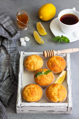Homemade lemon muffins with honey, mint and cup of tea for breakfast on a concrete background