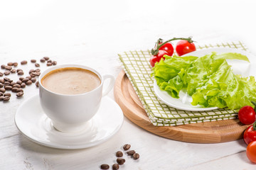 cup of coffee on a light background next to an empty plate for a future layout