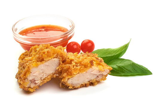 Fried Tasty Crispy Breaded Chicken Nuggets with basil leaves and spicy sauce, close-up, isolated on a white background.