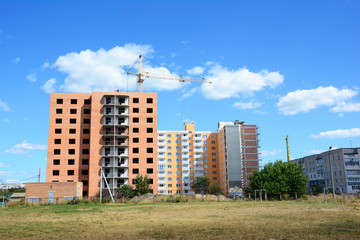Building crane and building under construction with insulation, paiting walls and building contractors.