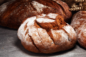 Different kinds of bread and bread rolls on board from above. Kitchen or bakery