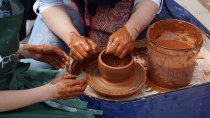 hands of potter creating jar on potters wheel