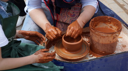 hands of potter creating jar on circle