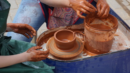hands of potter creating jar on potters wheel
