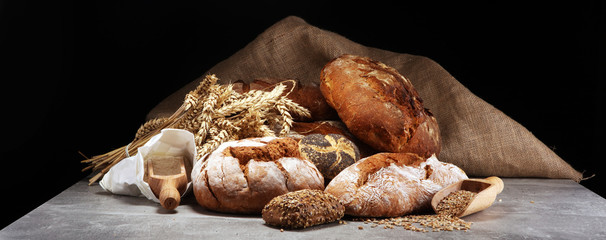 Different kinds of bread and bread rolls on board from above. Kitchen or bakery