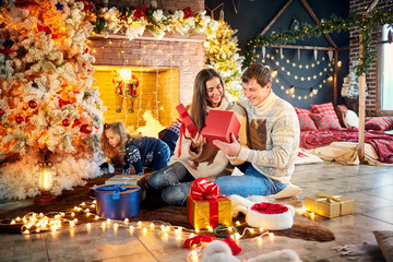 Family playing with gifts on the floor indoors on Christmas Day.