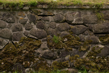 Fototapeta premium Anciend wall made of huge black stones with grass on its top. Korela Fortress, Russia