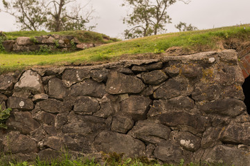 Anciend wall made of huge black stones with grass on its top. Korela Fortress, Russia