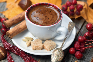 A cup of coffee with chili. Hot steaming cup with coffee. Autumn fall leaves.