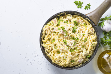 Pasta carbonara with bacon and cream sauce on white.