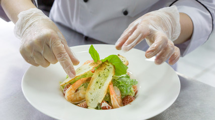 Chef preparing Caesar salad with shrimps