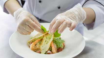 Chef preparing Caesar salad with shrimps