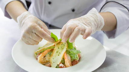 Chef preparing Caesar salad with shrimps
